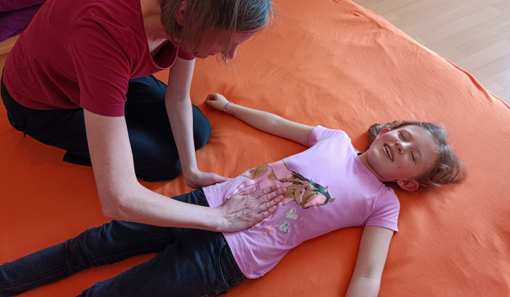 Shiatsu Behandlung für Kind am Rücken liegend am Bauch