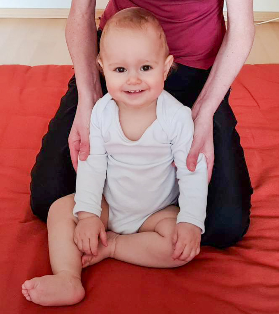 Shiatsu Behandlung für Baby an den Oberarmen in sitzender Position